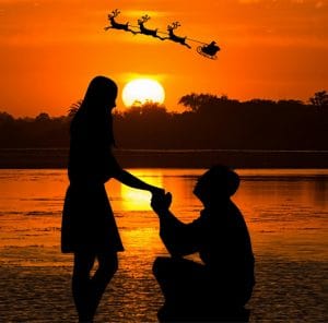 a man proposing to a woman in front of a lake at sunset with santa clause in his sled flying across the sky.